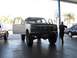 1986 Ford Bronco - White Ford Bronco with doors open, parked indoors with other vehicles nearby.