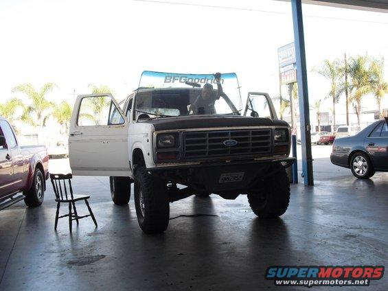 White Ford Bronco with doors open, lifted suspension, and BFGoodrich windshield banner