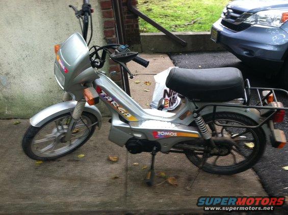 Silver moped with 'Targa' and 'Tomos' decals, parked outdoors