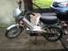 1999 Tomos Targa - A silver moped with 'Targa' and 'Tomos' branding is parked on a concrete surface next to a blue car.