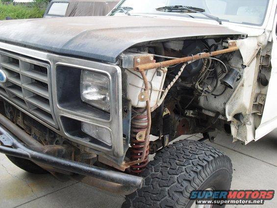 1980 Ford Bronco front end with grille, headlight, and exposed engine components. Off-road tire visible