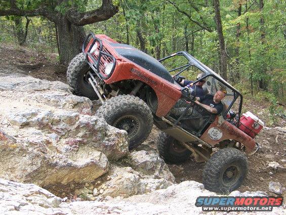 Red off-road vehicle climbing rocky terrain