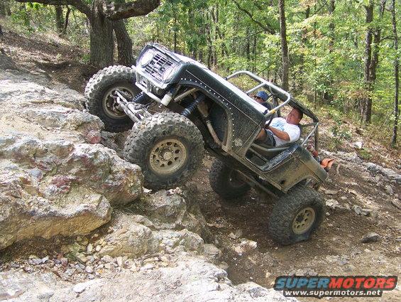 Off-road vehicle with large tires climbing a rocky incline