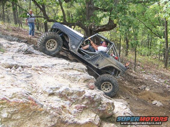 Off-road buggy climbing a rocky hill with a person watching