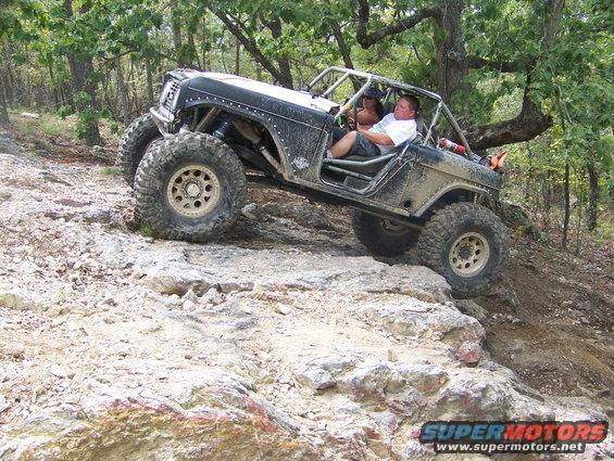 Modified off-road vehicle with large tires climbing a rocky incline
