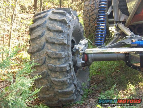 Off-road vehicle's large, aggressive tire and suspension components with blue coilover shock