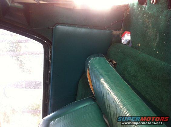 Green vinyl seats and carpet inside a vehicle, with a window on the left