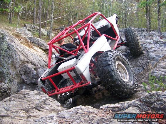 Off-road buggy with red roll cage climbing rocks