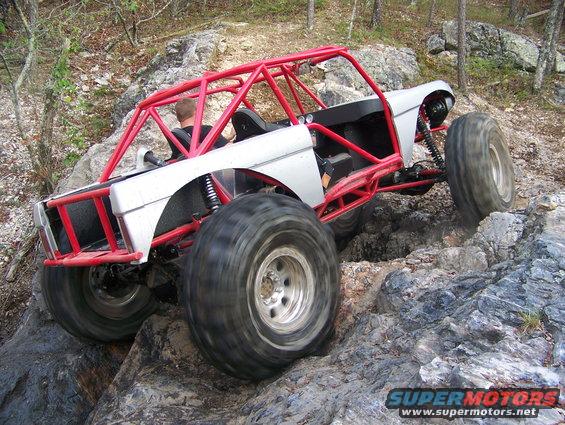 Off-road buggy with red roll cage climbing rocks