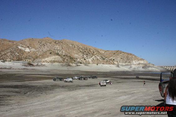 Several trucks and SUVs parked in a dry, dusty area with hills in the background
