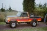 Orange and red striped Ford Bronco with a spare tire on the back, seen from the side