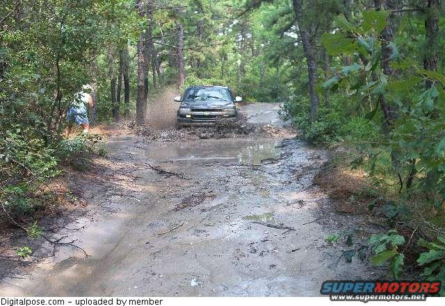 SUV splashing through a muddy trail in the woods