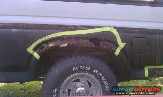 rusted out wheel well on a vehicle, taped off for repair