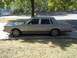 1988 Lincoln Town Car - This 1988 Lincoln Town Car is seen from the side, parked on a paved surface in front of a grassy area and trees.