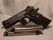 2003 Ford Crown Victoria - A black Kimber pistol rests next to a loaded magazine, its detailed craftsmanship.