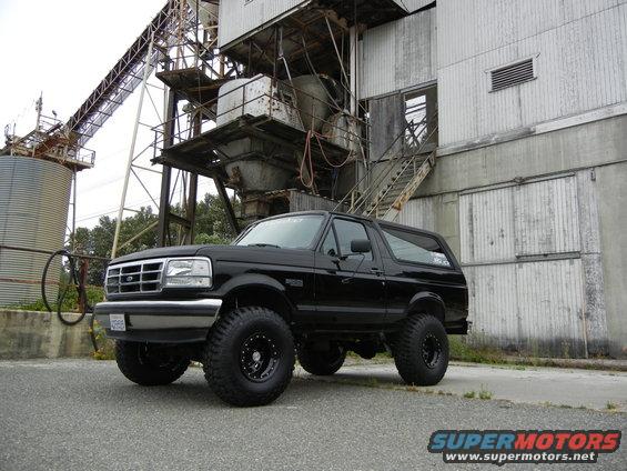 Black Ford Bronco with lifted suspension and off-road tires parked in front of an industrial building