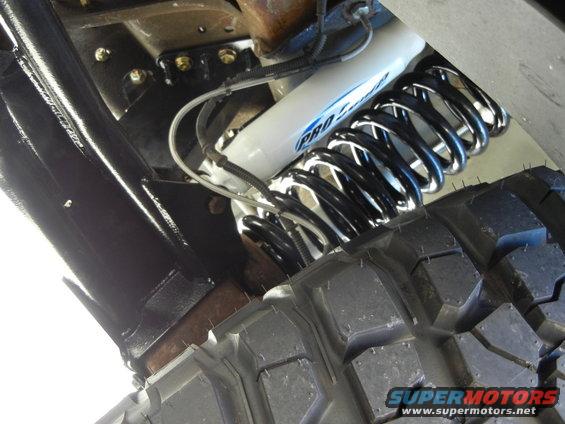 White Pro-Comp shock absorber and black coil spring with tire tread