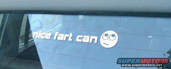 Car window with a sticker that says 'nice fart can' and a meme face