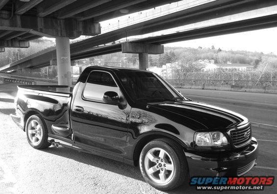 Black 2002 Ford F-150 Lightning pickup truck parked under an overpass
