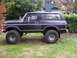1979 Ford Bronco - Side view of a black Ford Bronco, likely a 1978 model, with custom wheels and off-road tires.