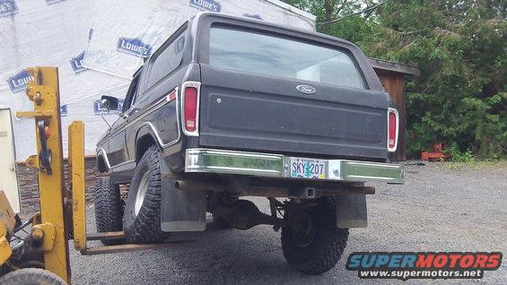Rear view of a black 1978 Ford Bronco with an Oregon license plate SKY 207, being lifted by a yellow forklift