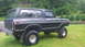 1979 Ford Bronco - This lifted black Ford Bronco is shown from a three-quarter rear view, parked on a grassy lawn.