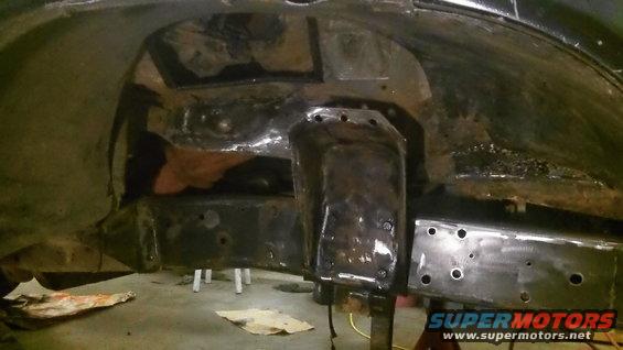 Blackened metal frame and suspension parts with visible welds and bolt holes