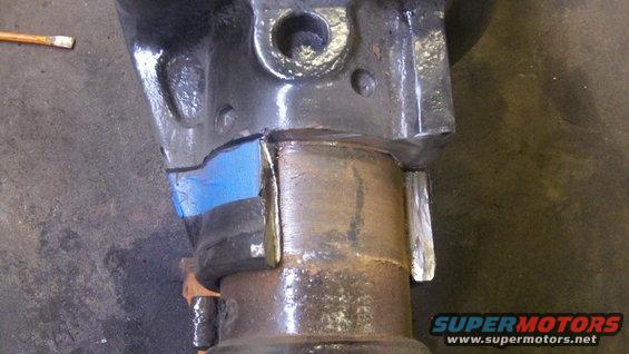Close-up of a differential housing with blue tape and metal plates attached, likely for modification