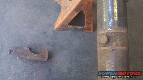 Rusty metal bracket and pipe section on concrete floor with orange jack stand