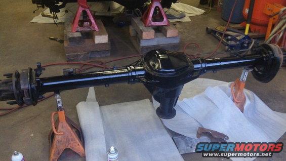 Black rear axle assembly on jack stands in a garage