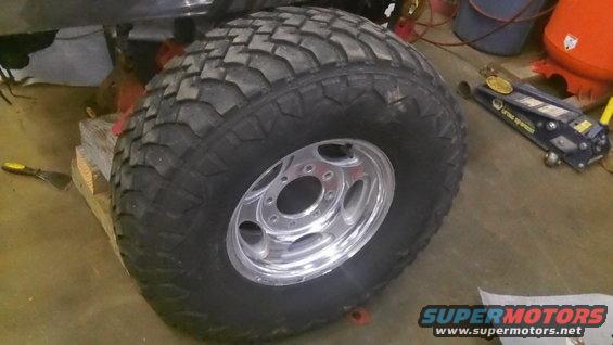 Large off-road tire on a chrome wheel, supported by wooden blocks