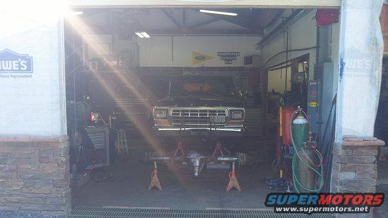1979 Ford Bronco front end raised on jack stands in garage, front axle removed
