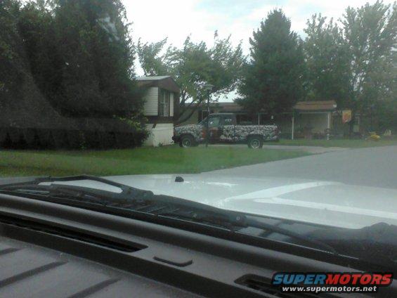 Pickup truck with camouflage wrap parked in front of a mobile home