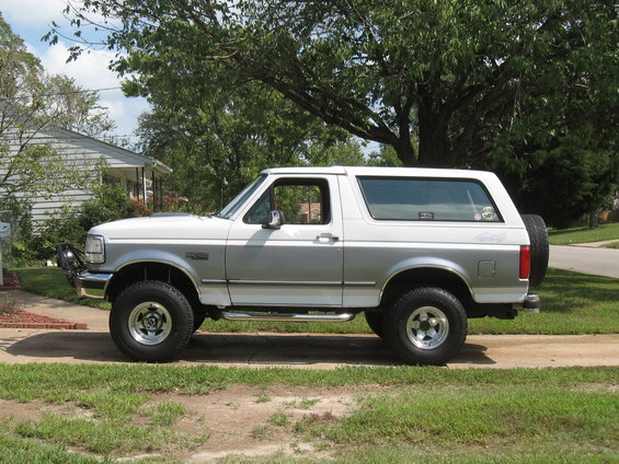Side view of a white and silver 1994 Ford Bronco with a spare tire on the back