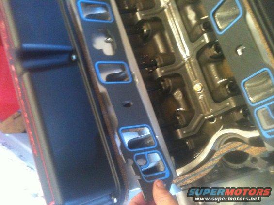 hand holding intake manifold gasket near engine block