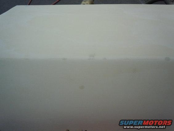 close-up of a light-colored car body panel, possibly primed for paint. Supermotors.net logo in lower right