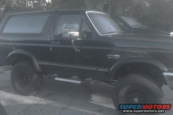 Black 1988 Ford Bronco parked on cracked pavement, "FOR SALE" sign in window