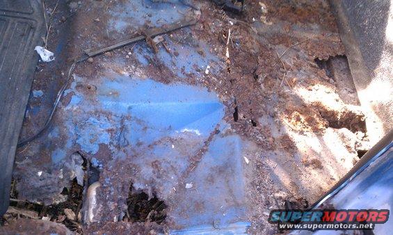 rusted out blue floor pan with holes, wires visible