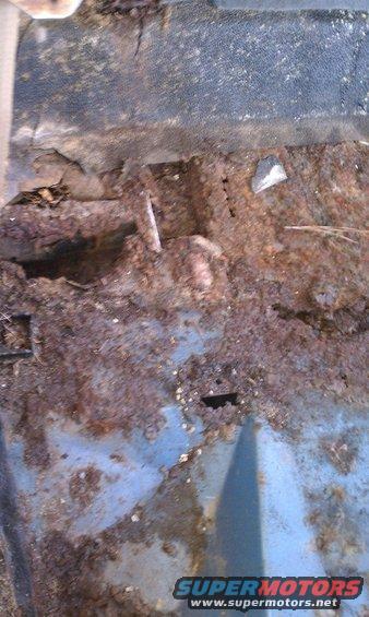 Heavily rusted interior floor pan with holes and debris