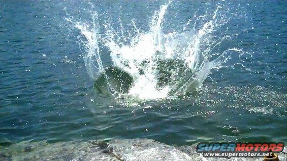 big splash in water, rocks in foreground, website logo at bottom right