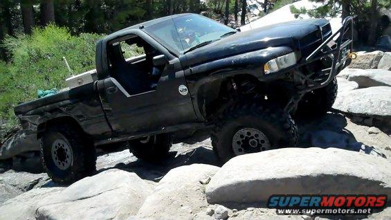 Black pickup truck with off-road modifications navigating rocky terrain