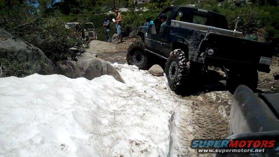 Black pickup truck navigating snow and rocks off-road