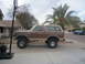 1985 Ford Bronco - Side view of a lifted 1985 Ford Bronco parked on a concrete driveway.