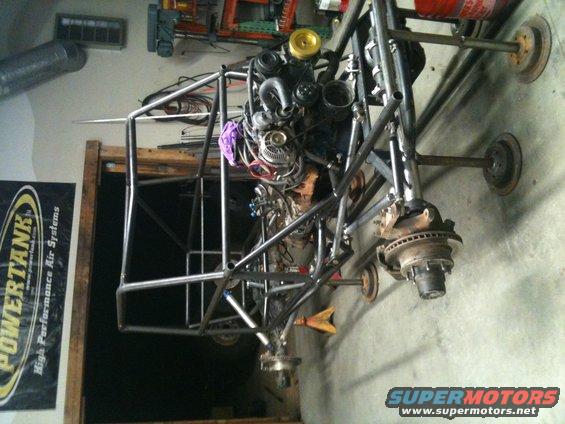 Custom buggy frame with engine and suspension components, in a garage