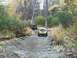 1979 Ford Bronco - Two SUVs navigate a water crossing on a wooded trail during the fall season.
