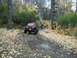 1979 Ford Bronco - A red Jeep Wrangler navigates a challenging off-road path through autumn foliage.