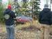 1979 Ford Bronco - Two people watch a red SUV navigate a wooded off-road trail.