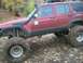 1979 Ford Bronco - This red SUV, equipped for off-roading with a snorkel and oversized tires, navigates a leaf-strewn path.