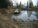1979 Ford Bronco - Several off-road vehicles navigate a muddy trail during autumn, kicking up water and mud.
