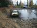 1979 Ford Bronco - Two SUVs tackle a challenging muddy off-road course during autumn.